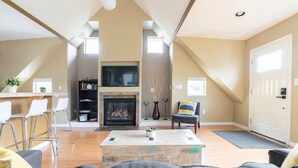 A spacious loft apartment with high ceilings, a fireplace, a TV, and a dining area with bar stools. - Spacious Studio Apartment Minutes from Downtown, Private Parking  (Seattle)