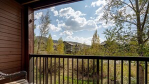 Un balcón de madera con vistas a una zona residencial, que incluye casas y árboles.