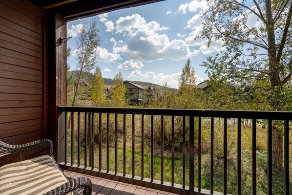 Un balcón de madera con vistas a una zona residencial, que incluye casas y árboles.