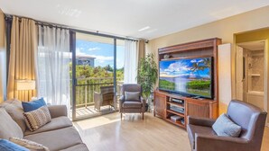 Ein geräumiges Wohnzimmer mit großem Flachbildfernseher, bequemen Sitzmöglichkeiten, einem Balkon mit Meerblick und einem modernen Interieur.