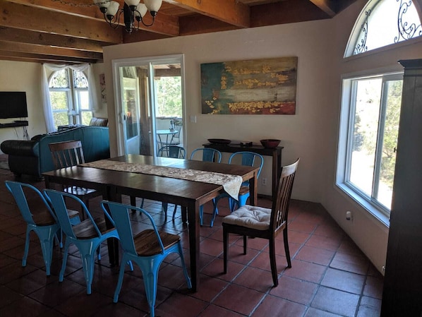 A dining area with a wooden table, blue chairs, and a painting on the wall. - The 'White Castle' Riverfront Home with Park Views! (Three Rivers)