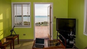 A room with a view of the sea, a TV, and a laptop on a table.