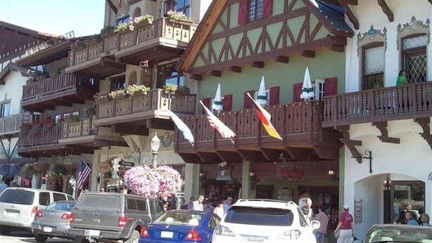 Un edificio europeo tradicional con un balcón, un reloj y banderas.