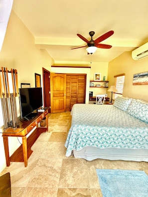 A bedroom with a bed, a television, a desk, and a wardrobe.
