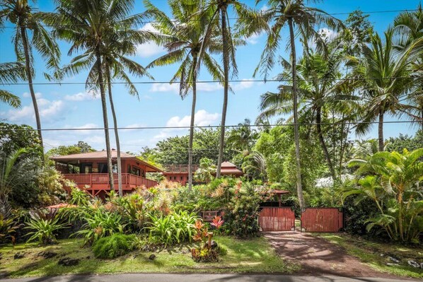 A tropical resort with a two-story building, lush greenery, and palm trees.