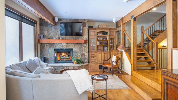 Una sala de estar acogedora con chimenea, escalera de madera y un espacio de descanso confortable.