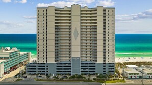 A multi-story hotel with a central atrium, a parking garage, and a beach view.