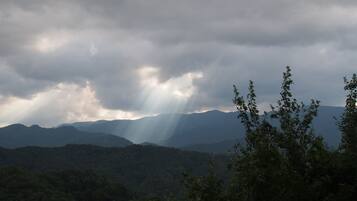 A mountainous landscape with dense forest and sunlight filtering through clouds.