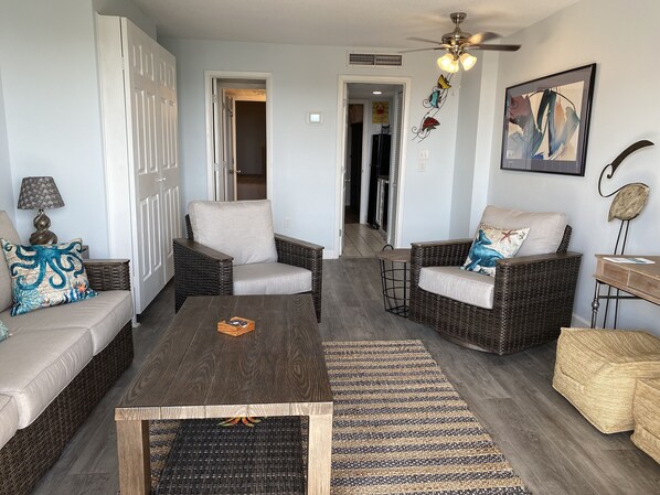 A living room with wicker furniture, a ceiling fan, and a framed abstract painting. - Relaxation Station!  Enjoy a very quiet, calm area of Myrtle Beach at our condo. (Myrtle Beach)