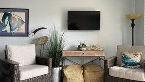 A living room with wicker furniture, a flat-screen TV, and a potted plant. - Relaxation Station!  Enjoy a very quiet, calm area of Myrtle Beach at our condo. (Myrtle Beach)