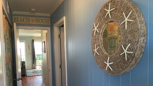 A hallway with a sign reading "BEACH HOUSE" and a woven wall hanging with starfish. - Isle of Palms - 3rd Floor Ocean Front with Private Balcony, Pool, and Pier  (Isle of Palms)