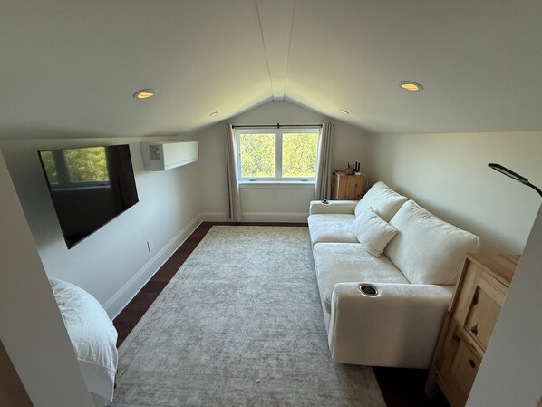 A small, well-lit room with a white sofa, a wooden cabinet, a window, and a ceiling with recessed lighting. - Large Outdoor Kitchen, Pool, Hot Tub, Firepit...8 Mins From Healdsburg Plaza (Healdsburg)