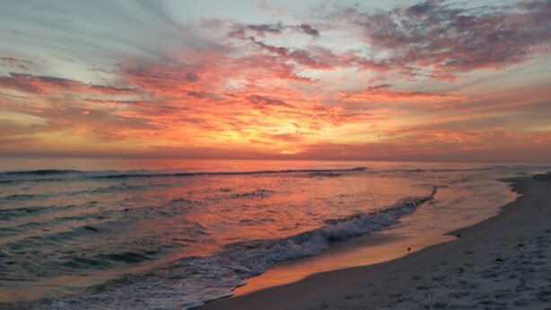 Una playa con olas y un atardecer.