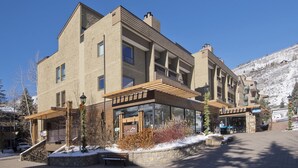 A modern multi-story hotel with a stone facade, large windows, and a covered outdoor area with a bench.