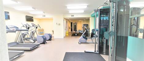 A gym with treadmills, elliptical machines, and weightlifting equipment.