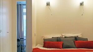 Un dormitorio con una cama, un escritorio y una silla al fondo.