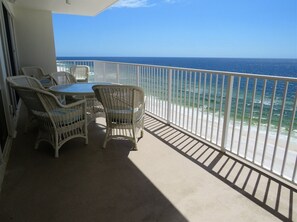 A balcony with wicker furniture and a view of the ocean.