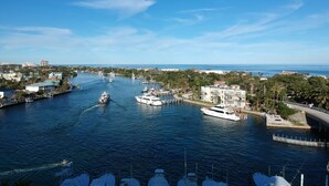 A marina with multiple boats docked, a clear blue sky, and a view of the cityscape in the background.
