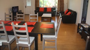 A dining area with a table and chairs, a sofa, and a television in a living room.