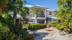 A large, two-story building with a white facade, a balcony, and a covered outdoor area. - LUXURY WATERFRONT ESTATE SEAWALL DOCKAGE & POOL (Key West)