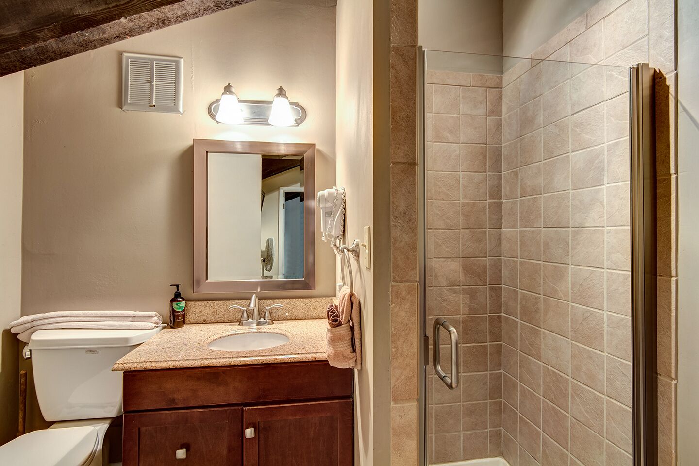 A bathroom with a sink, mirror, and shower.