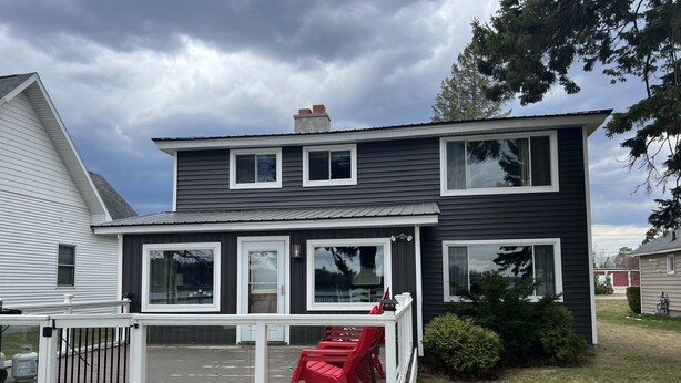A two-story house with a front deck and a red chair. - FAMILY FRIENDLY COTTAGE SLEEPS 12 !!! BEAUTIFULLY UPDATED (Petoskey)