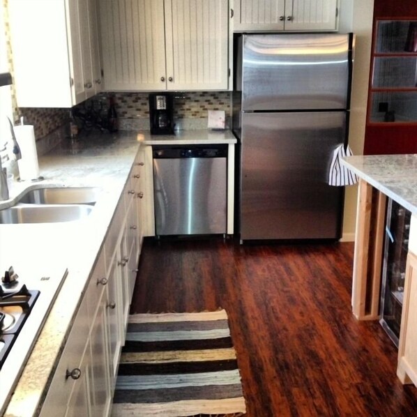 A kitchen with white cabinets, a stainless steel refrigerator, a dishwasher, and a wooden floor. - FAMILY FRIENDLY COTTAGE SLEEPS 12 !!! BEAUTIFULLY UPDATED (Petoskey)