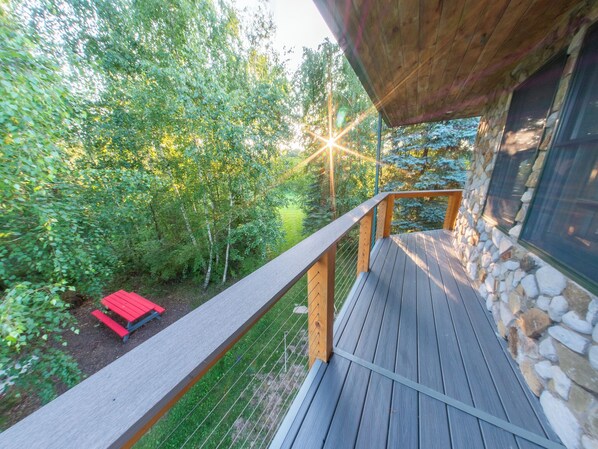 Eine Holzterrasse mit einer Steinmauer, umgeben von Grünpflanzen und einer roten Bank.
