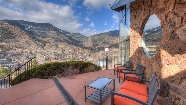 Una terrazza con posti a sedere all'aperto, un muro in pietra e vista su un paesaggio montuoso.