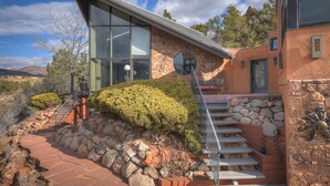Una casa moderna con facciata in pietra, una veranda in vetro e una scalinata in pietra che conduce a una porta.