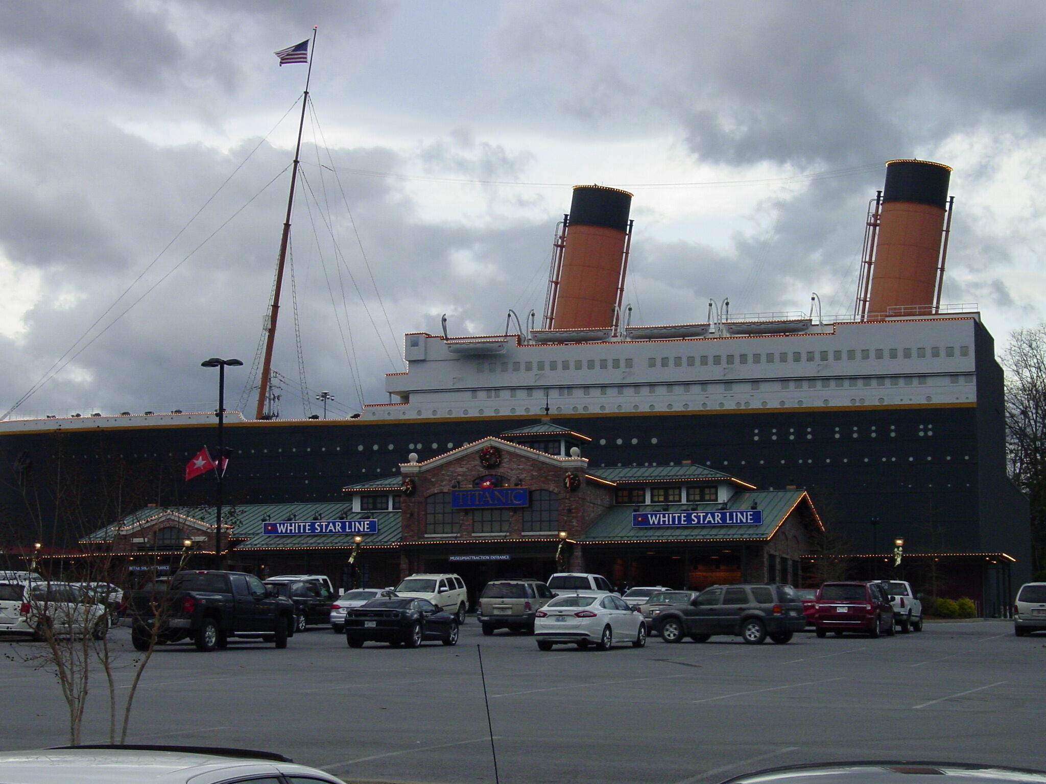 A large building with two prominent smokestacks, a flagpole with an American flag, and signage for 'White Star Line' and 'White Star Line Hotel'.