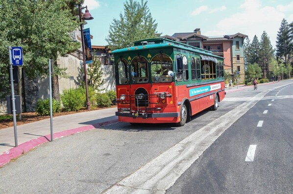 Ein rot-grüner Trolleybus fährt auf einer Straße mit einer Fußgängerampel.