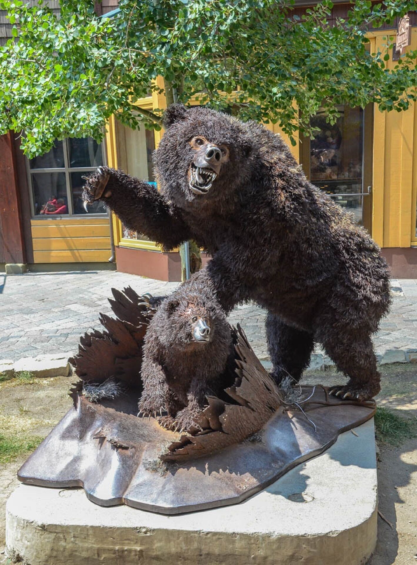 Una estatua de oso sobre un pedestal de hormigón al aire libre.