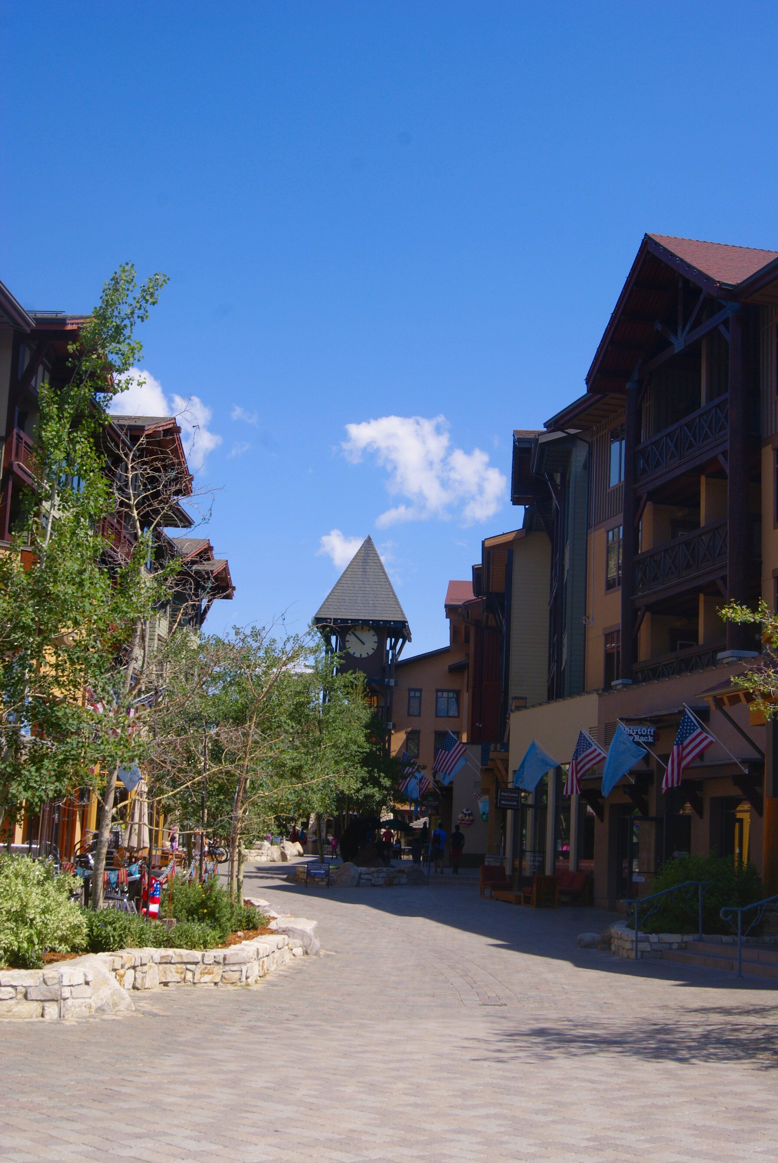 A town square with buildings featuring balconies and a clock tower.
