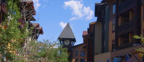 A town square with buildings featuring balconies and a clock tower.