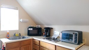 A small kitchen with a sink, a microwave, a coffee maker, and a toaster. - Kenai River Cabins Front (Soldotna)