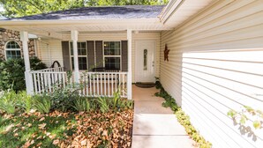 A house with a covered porch, a stone wall, and a front door.