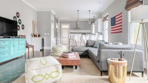 A modern living room with a grey sofa, a teal cabinet, and a coffee table with books. - Spacious Designer Gem, Dog Friendly, Private Patio    |   Grill, Patio 3 Blocks to Grocery, 5 Mins to 5 Points, 15 Mins to Broadway, 24 Hour Hospitality Team, Perfect for Families (Nashville)