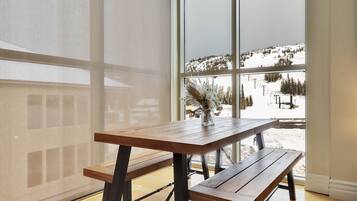 Une table et un banc en bois se trouvent à l’intérieur d’une pièce dotée de grandes fenêtres donnant sur un paysage enneigé.