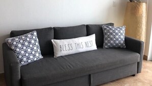 A grey sofa with patterned cushions and a wall-mounted abstract painting. - Location,Location,Location "Casa Gelma" WATERFRONT  (Isla Verde)