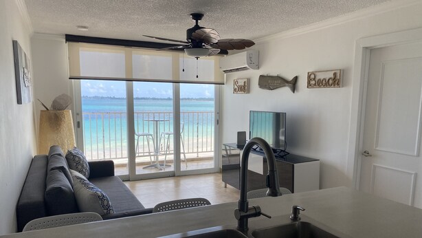 A modern kitchen with a large island, a dining area with a view of the beach, and a ceiling fan. - Location,Location,Location "Casa Gelma" WATERFRONT  (Isla Verde)