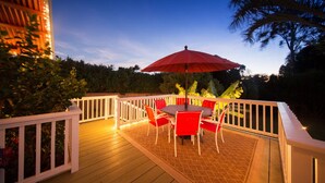 An outdoor deck with a table and chairs, surrounded by a white railing.