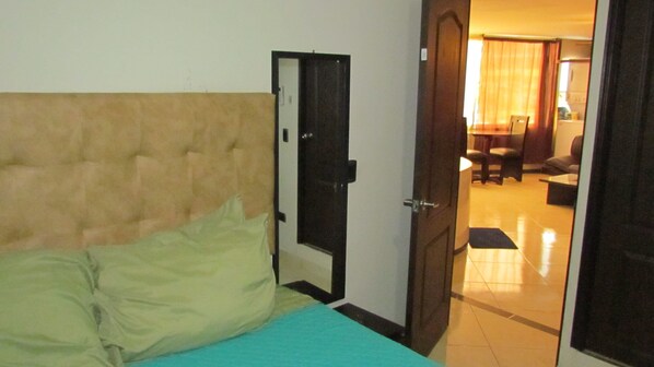 A hotel room with a bed, a door leading to a living area, and a tiled floor. - 3rd Floor 2 bedroom (Medellín)