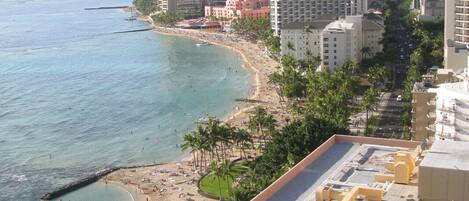 Un paysage urbain côtier avec une plage, des immeubles de grande hauteur et un ciel dégagé.