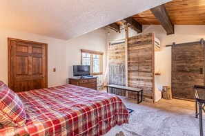 Une chambre à coucher avec un lit, des murs en bois, une télévision et une fenêtre.