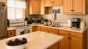 A kitchen with wooden cabinets, a microwave, a coffee maker, and a bowl of pinecones. - Romantic Mountain Cabin | Near Bryce & Zion (Duck Creek Village)