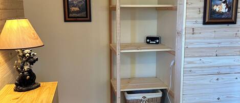 A wooden room with a built-in wardrobe, a lamp, and two framed pictures on the wall.