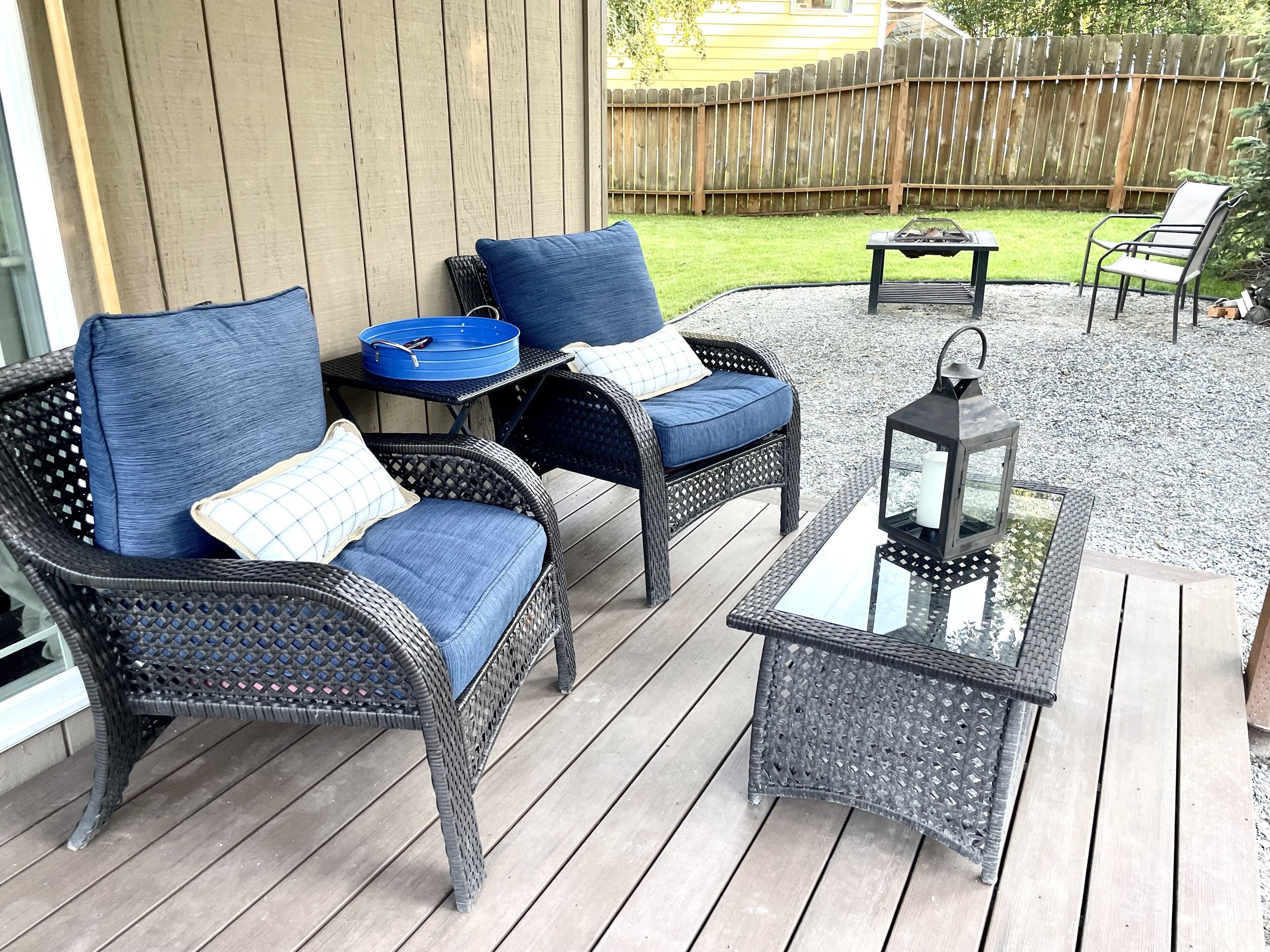 Une terrasse dotée de meubles en osier, notamment deux chaises et une table, ainsi que d’une lanterne.