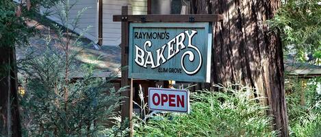 A sign for Raymond's Bakery with an 'OPEN' sign below it.