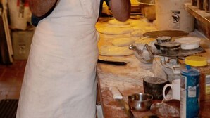Une personne se trouve dans une cuisine équipée d’une hotte en acier inoxydable, d’un rouleau à pâtisserie et de divers ustensiles de cuisine disposés sur le plan de travail.